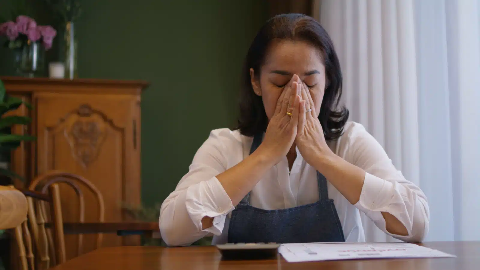 An upset woman covers her face after making a mistake.