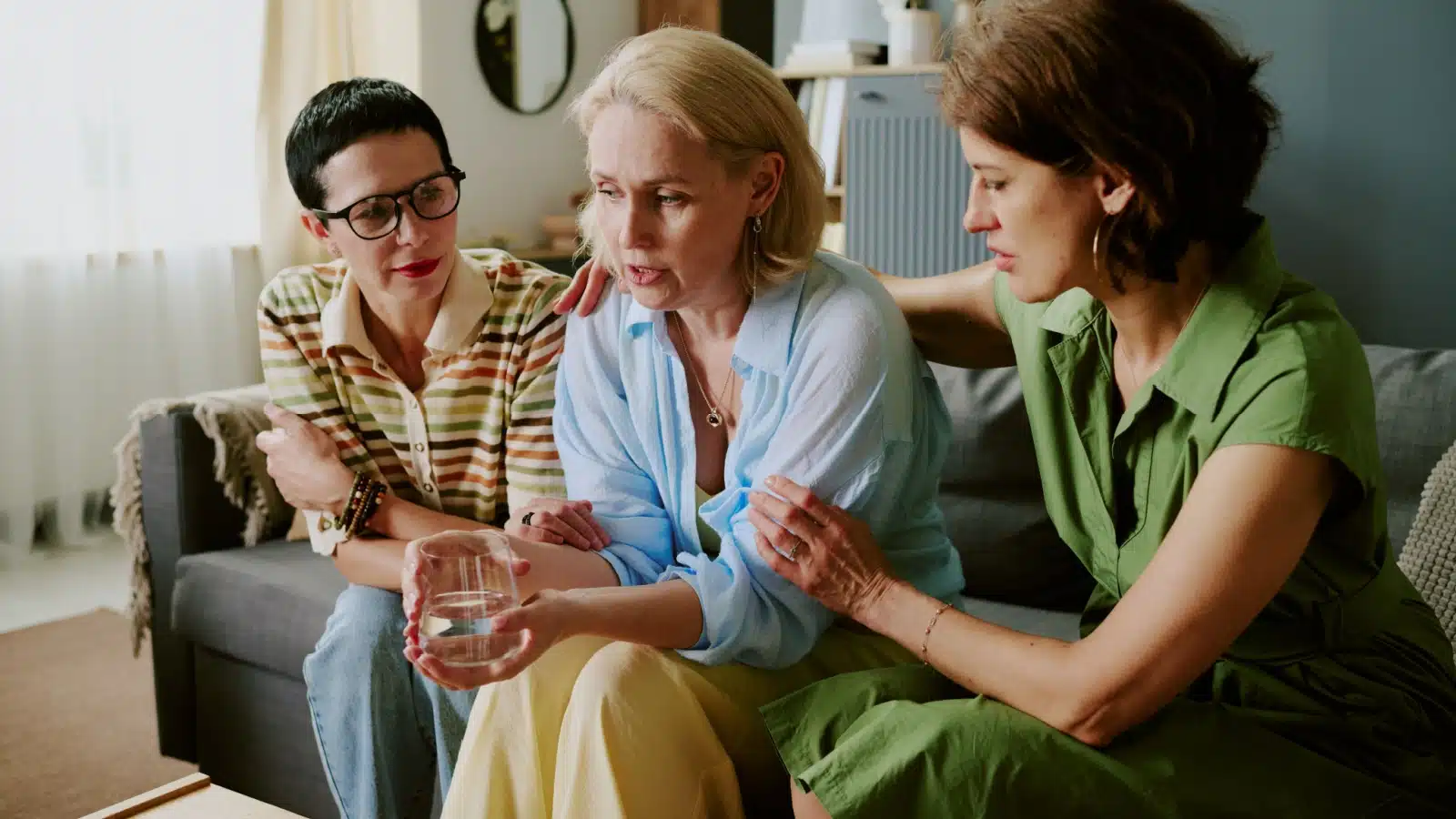 Two women are comforting their sad friend to represent emotional labor.