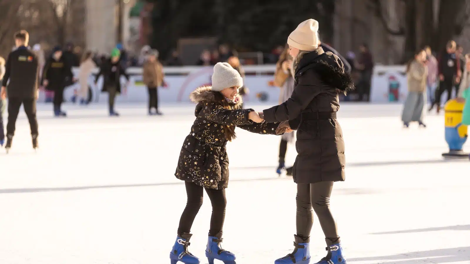 A mother and daughter ice skating together.