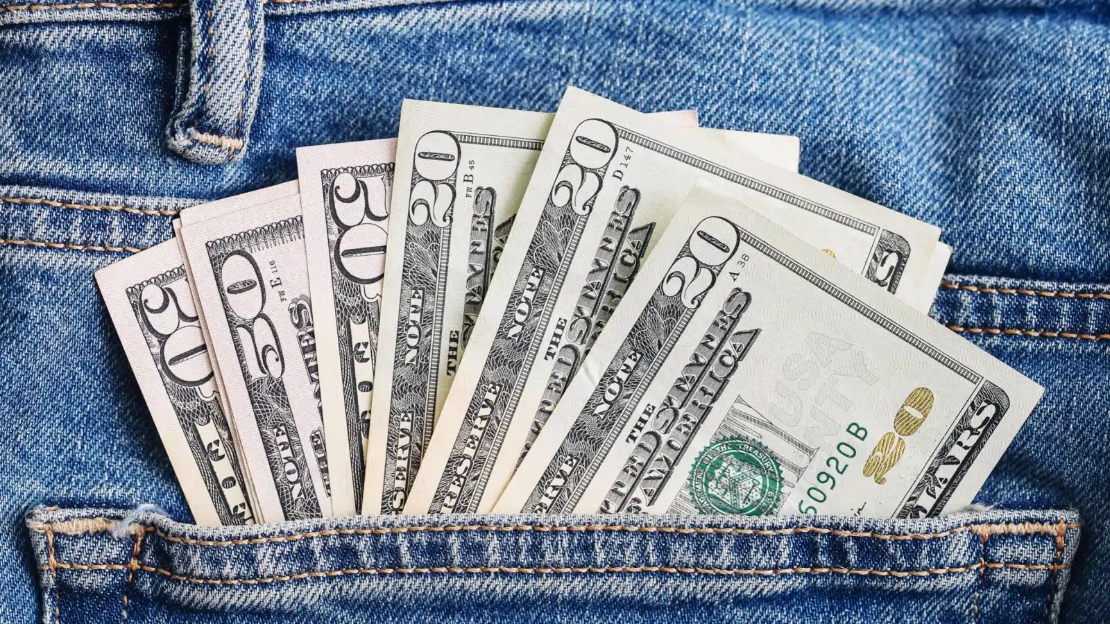 A jeans pocket stuffed with $20 bills to represent pocket cash.