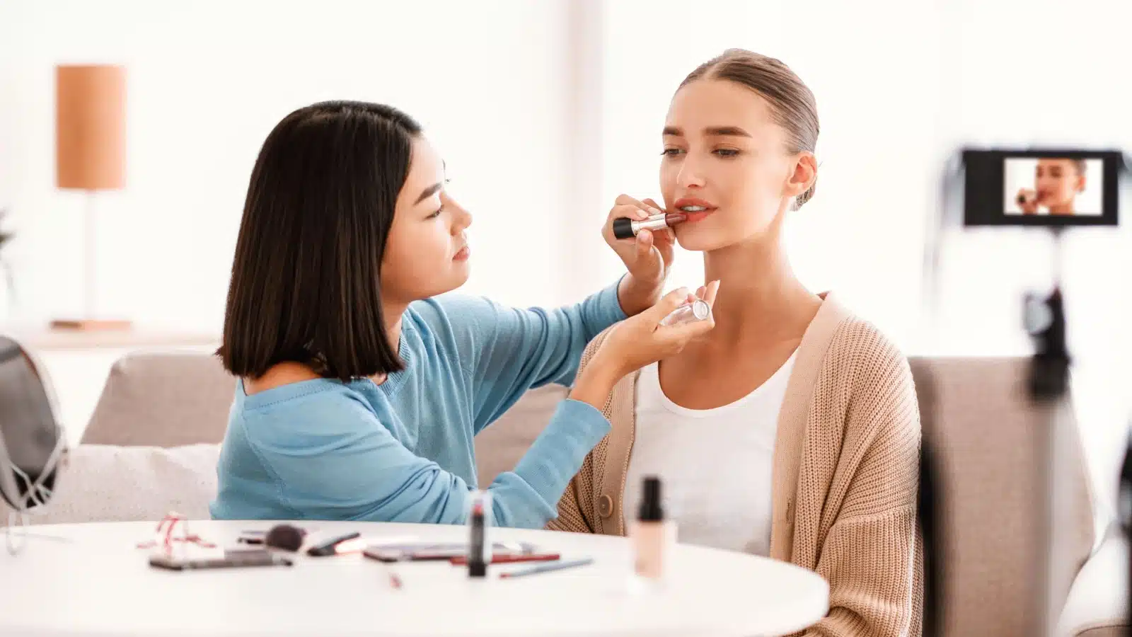 A woman lets an influencer test a new color of lipstick on her.