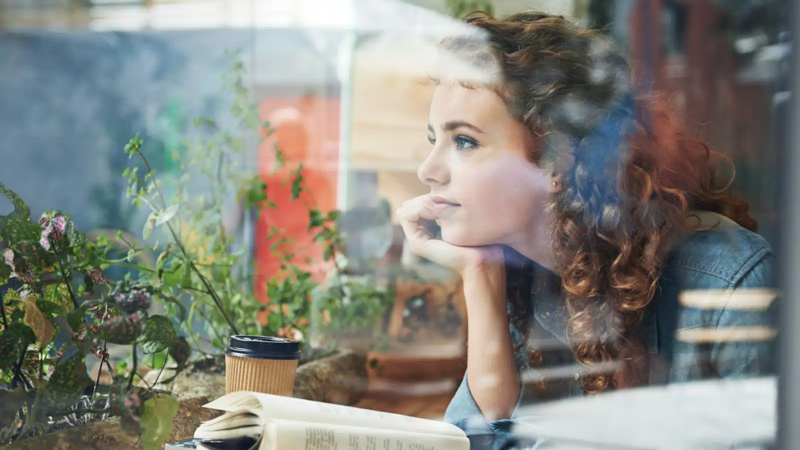 A woman stares out the window, daydreaming.