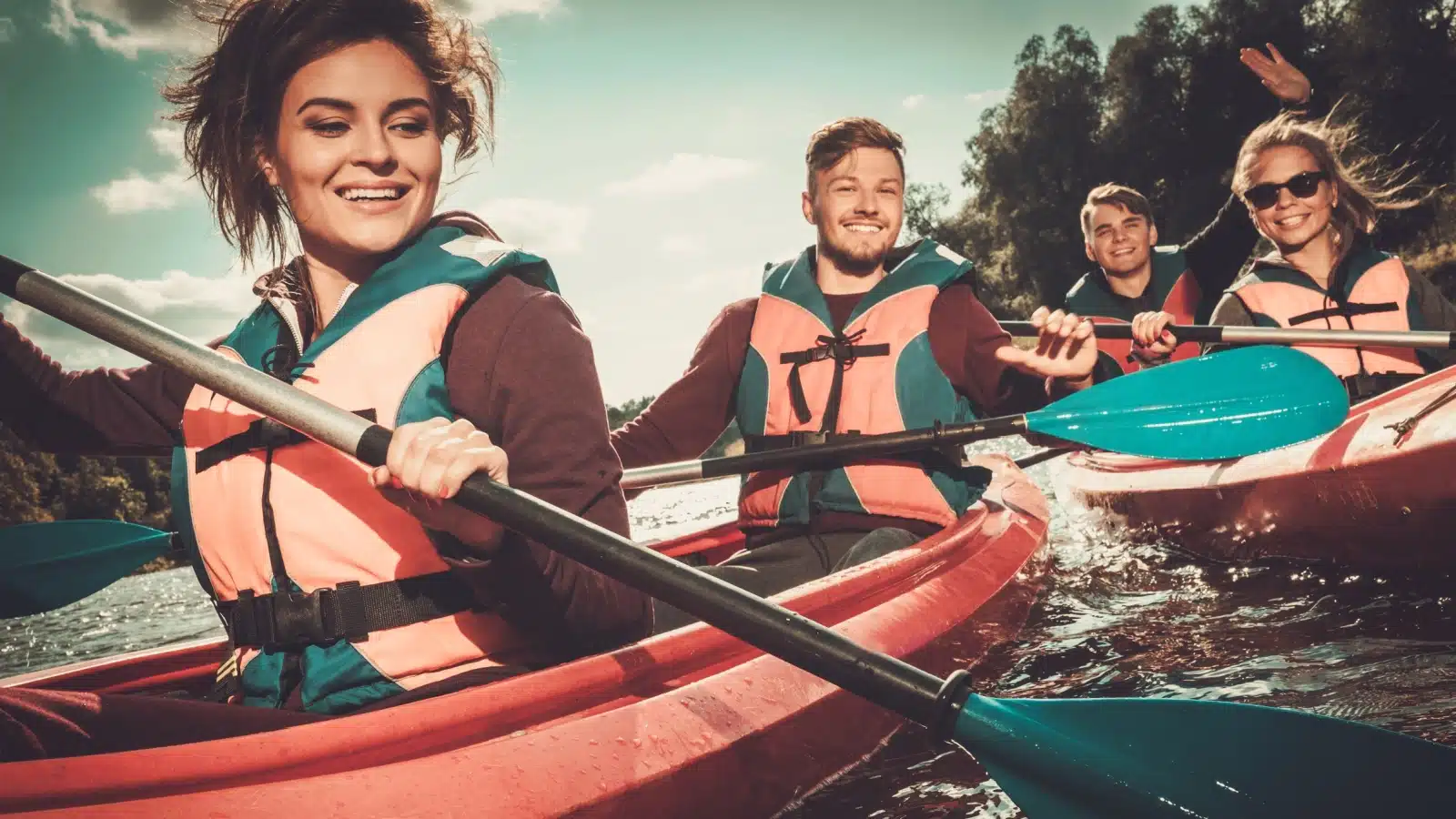 A group of happy friends challenge themselves with a kayak adventure.