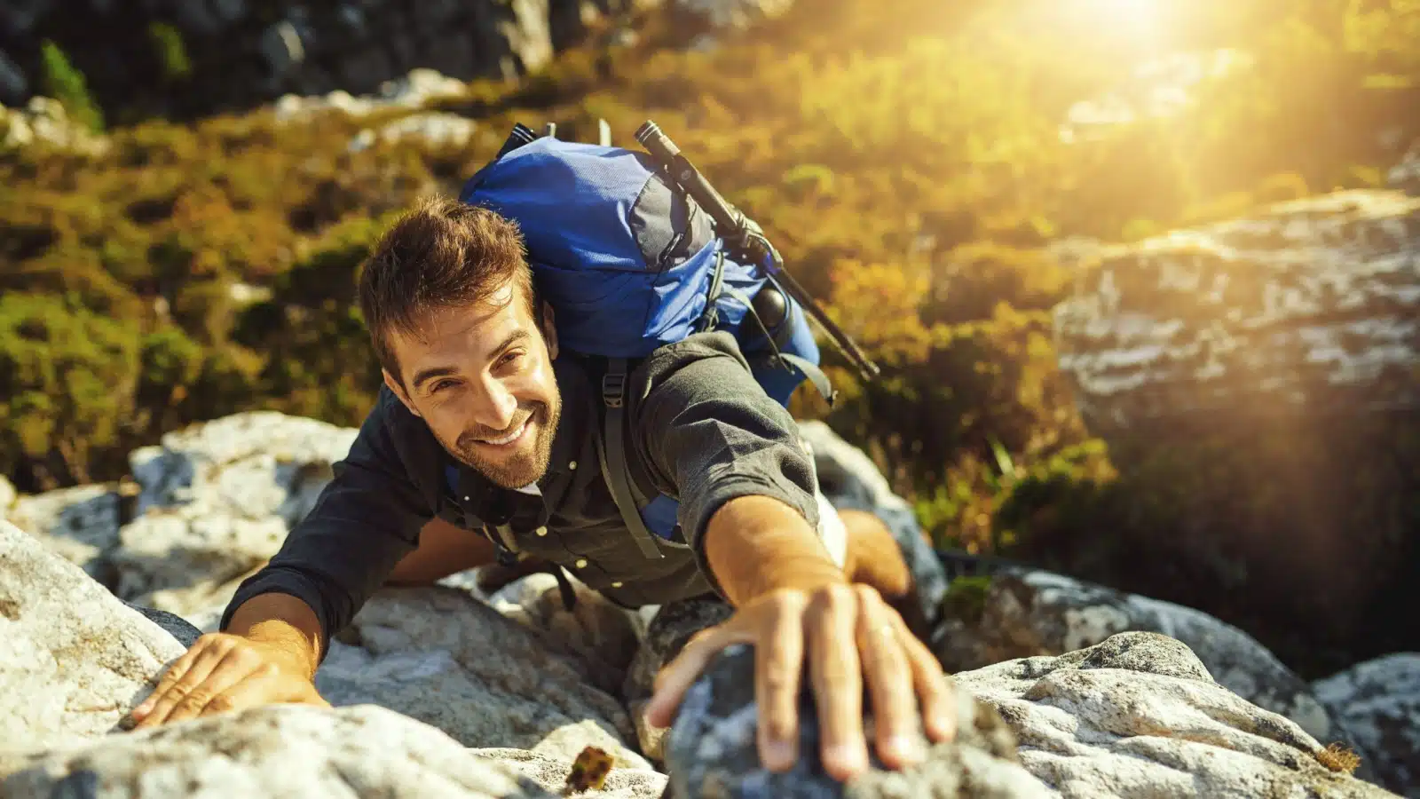 A happy man challenges himself by climbing a mountain.
