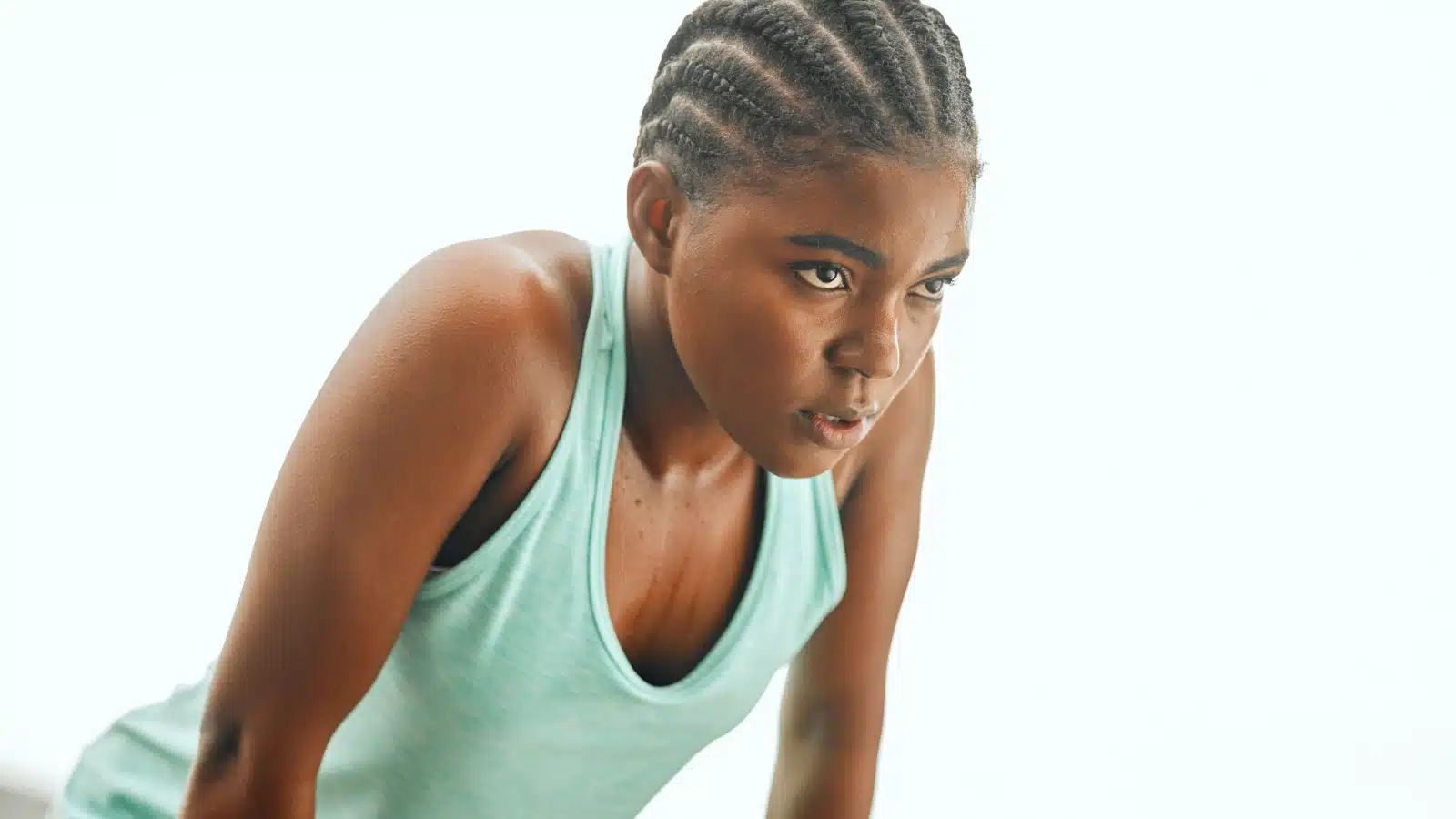 A woman leans over sweating after pushing herself. But her face is set to try again. She embodies resilience.