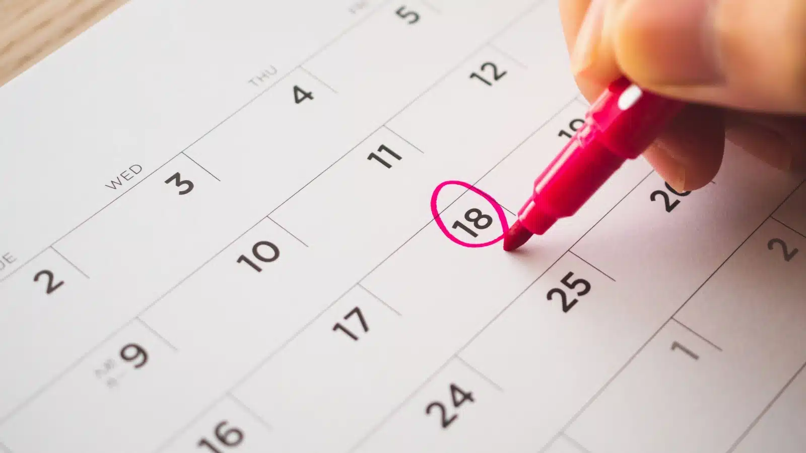 A close up of someone using a marker to circle a date on a calendar, setting a deadline.