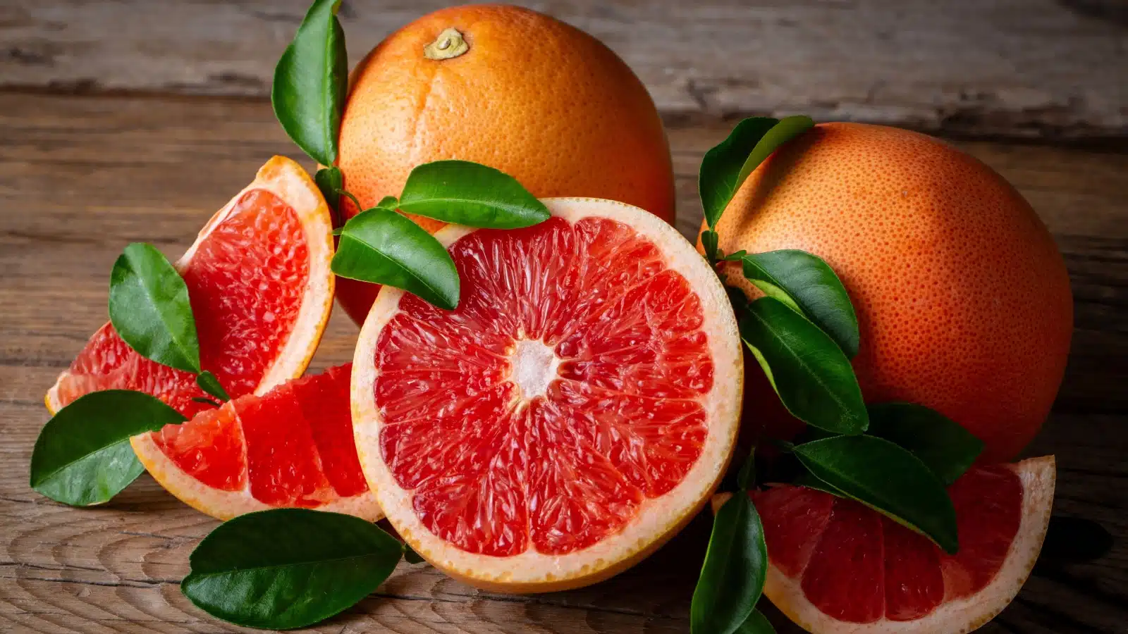 Freshly cut grapefruit on a table with uncut fruits.
