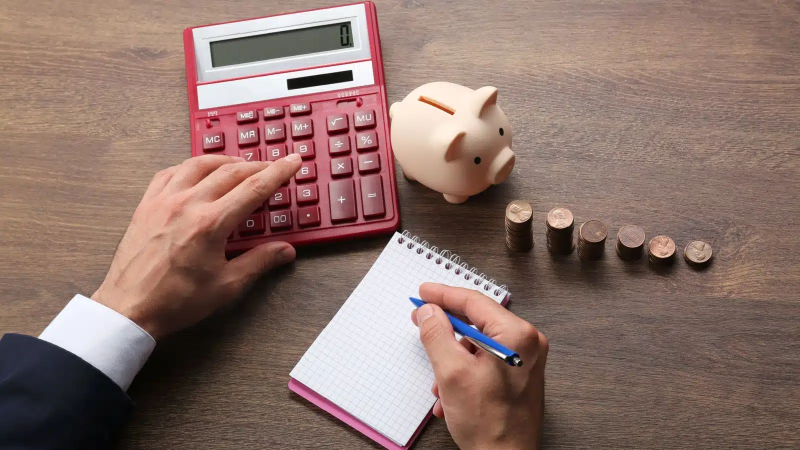 A man uses simple budgeting tools like a calculator and notepad to write out his budget.