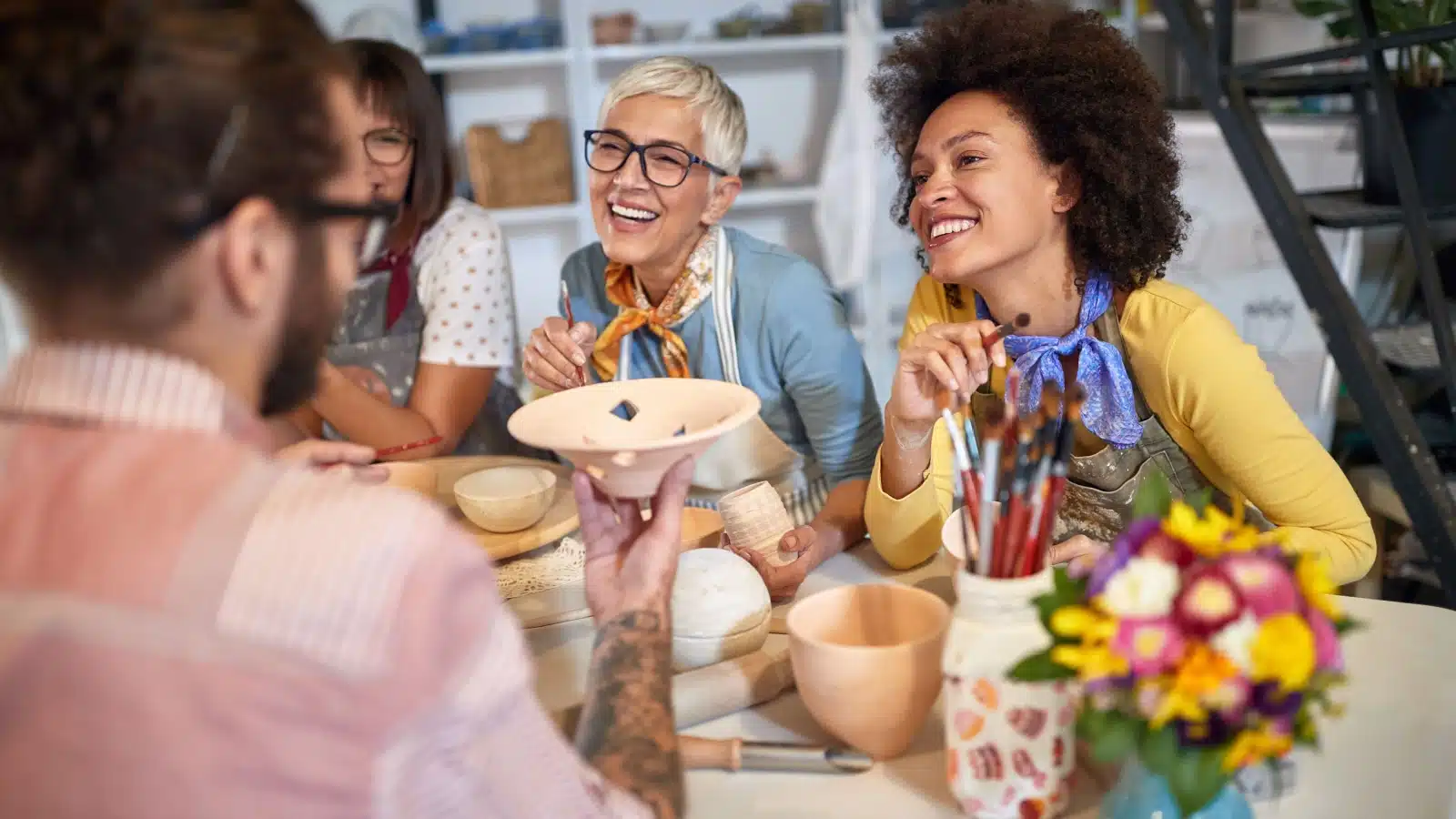 A group of friends enjoying crafting hobbies together. They are making and painting pottery.