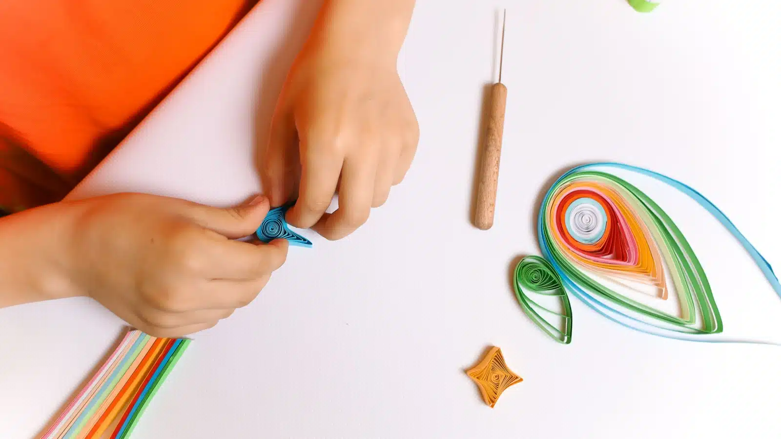A child's hands quilling paper.