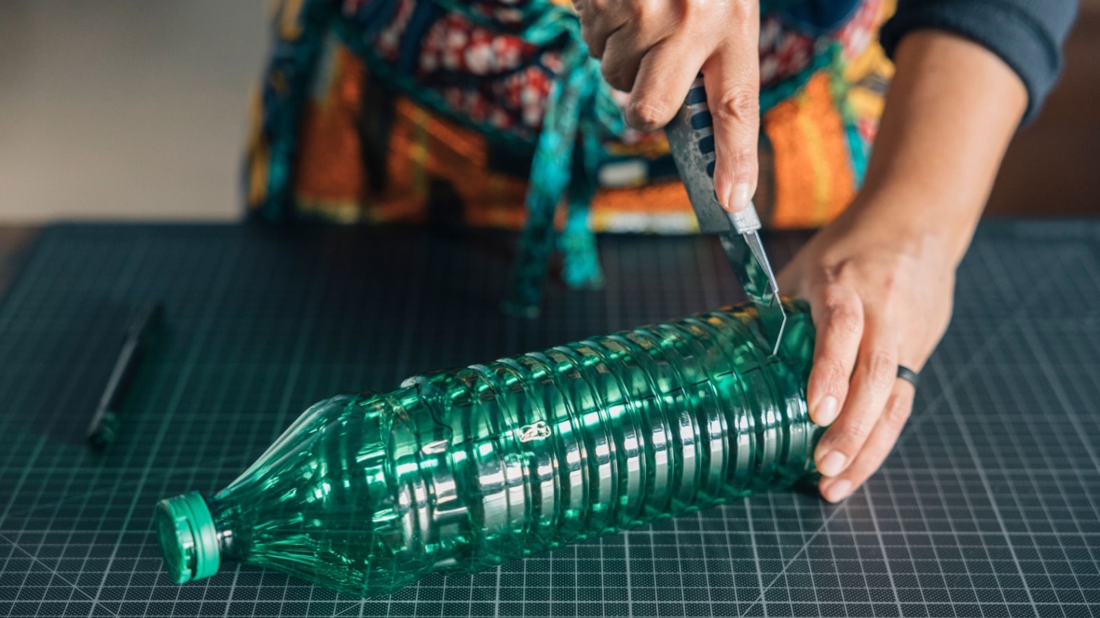 A woman carves a plastic bottle to upcycle it.