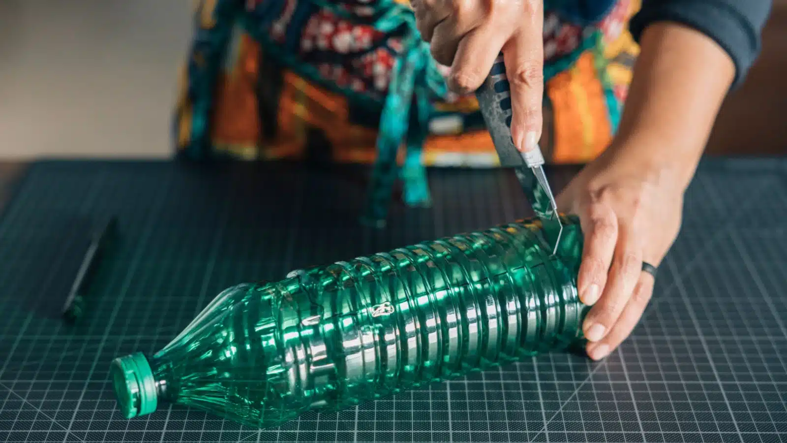 A woman carves a plastic bottle to upcycle it.