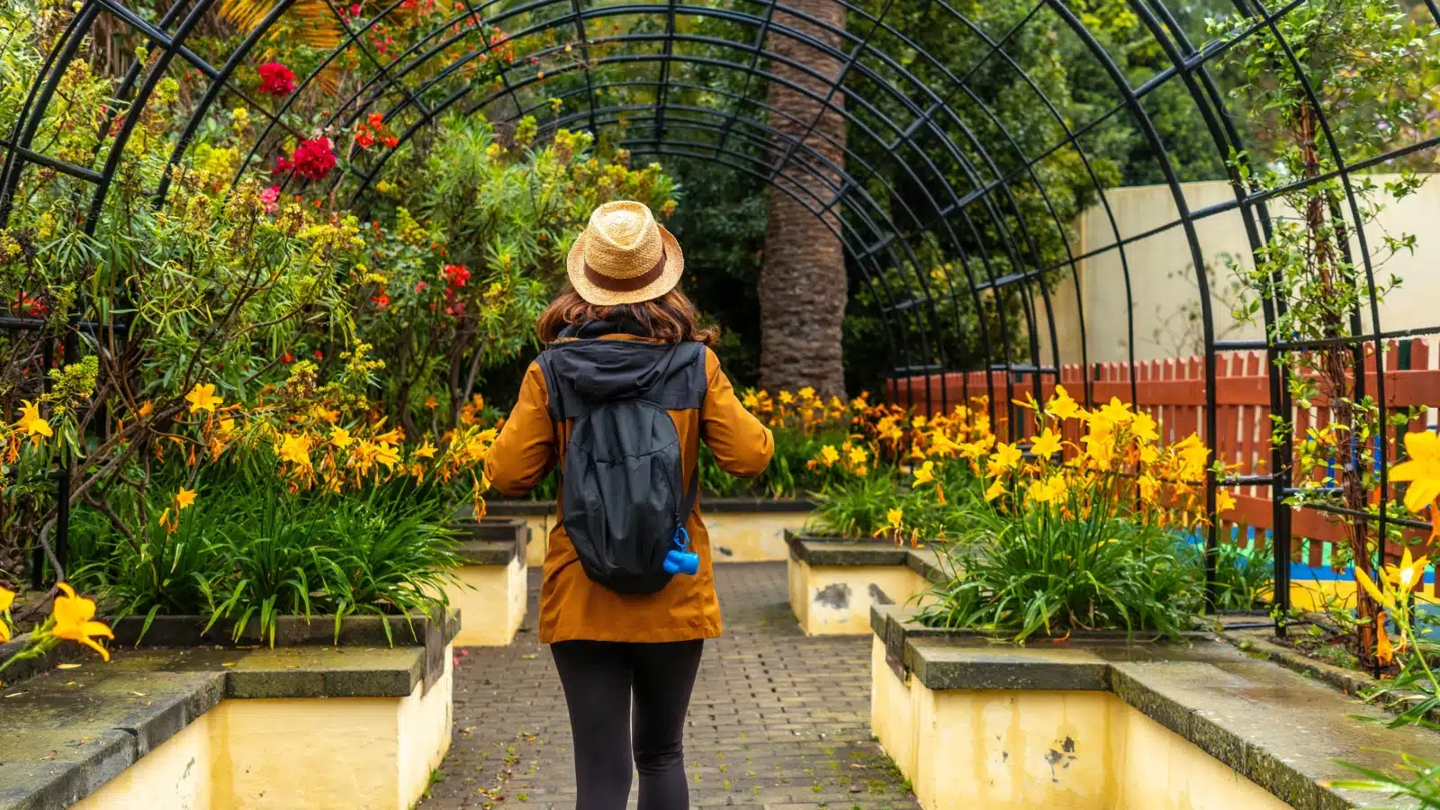 A woman walks through a greenhouse at a botanical garden.