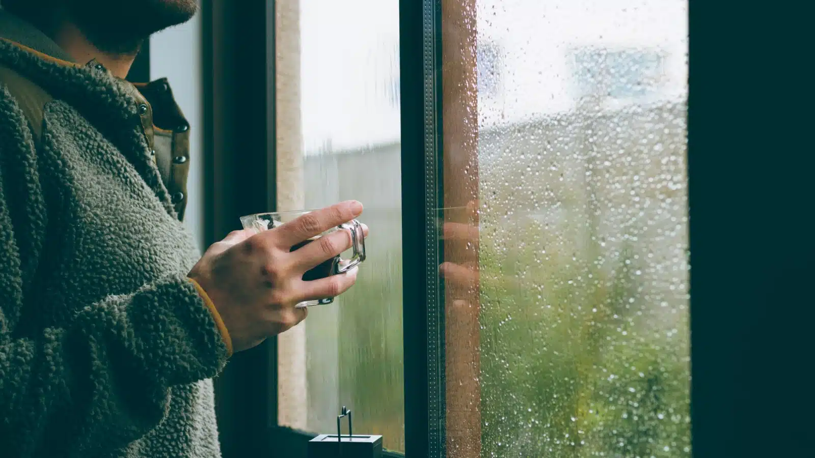 A man watches the rain from his window.