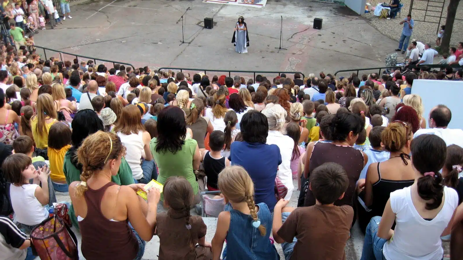 A crowd enjoys a performance at an outdoor theater.