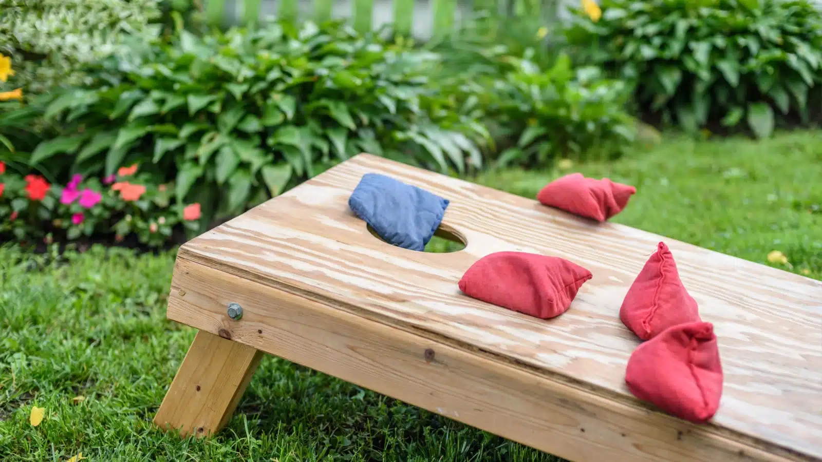 A plain wooden cornhole ramp with sandbags on it.