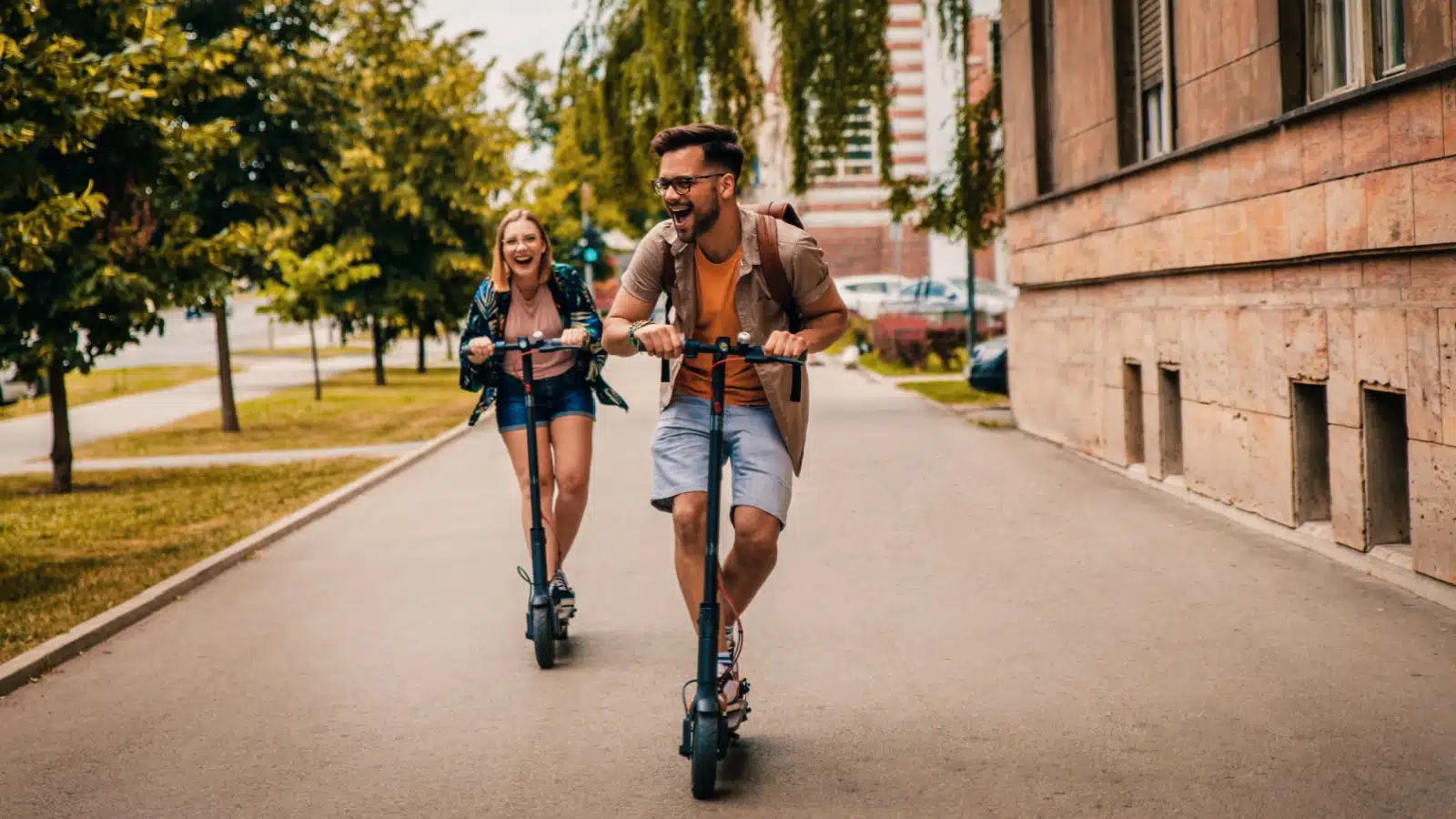 A young couple zips around town on rented scooters, enjoying the summer day.