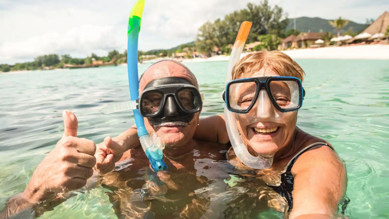 A senior couple takes a selfie while snorkeling.