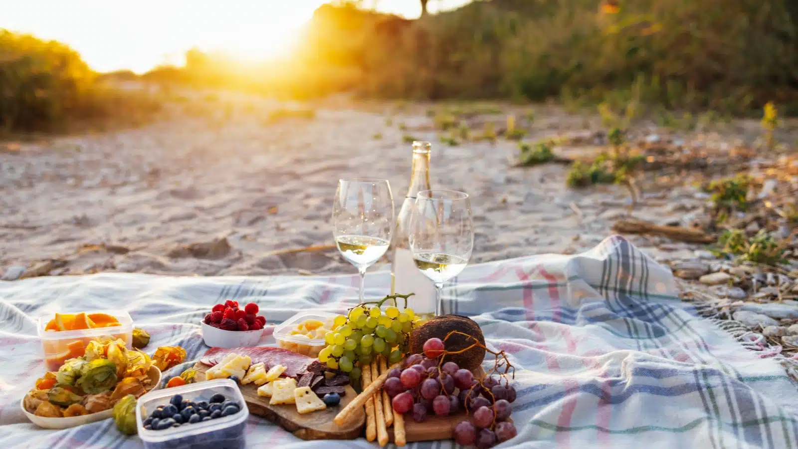 A blanket, food, and wine set up for a sunset picnic.