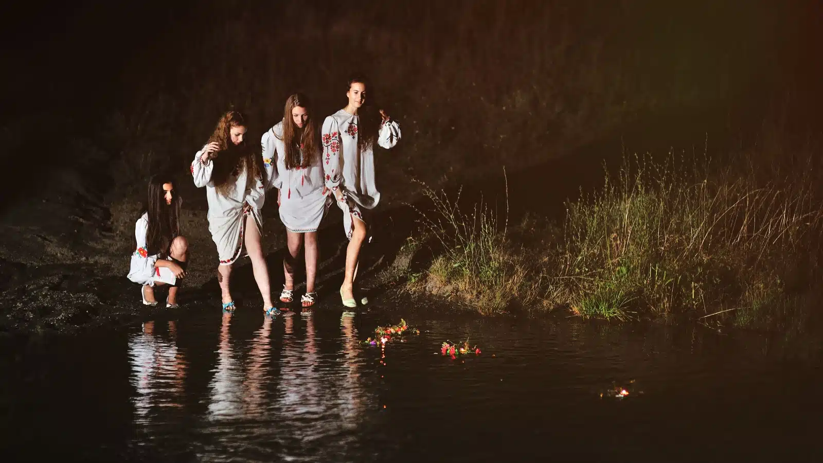 Four girls getting into a lake on Ivan Kupala Night to celebrate the summer solstice.