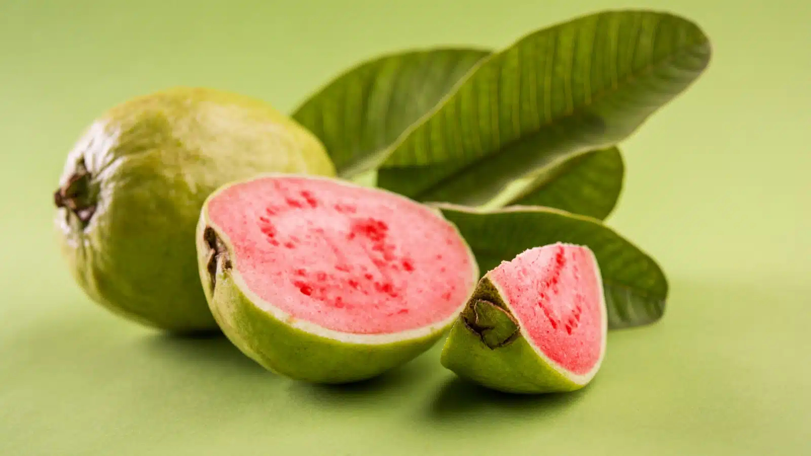 Freshly cut guava fruit isolated on a green background.