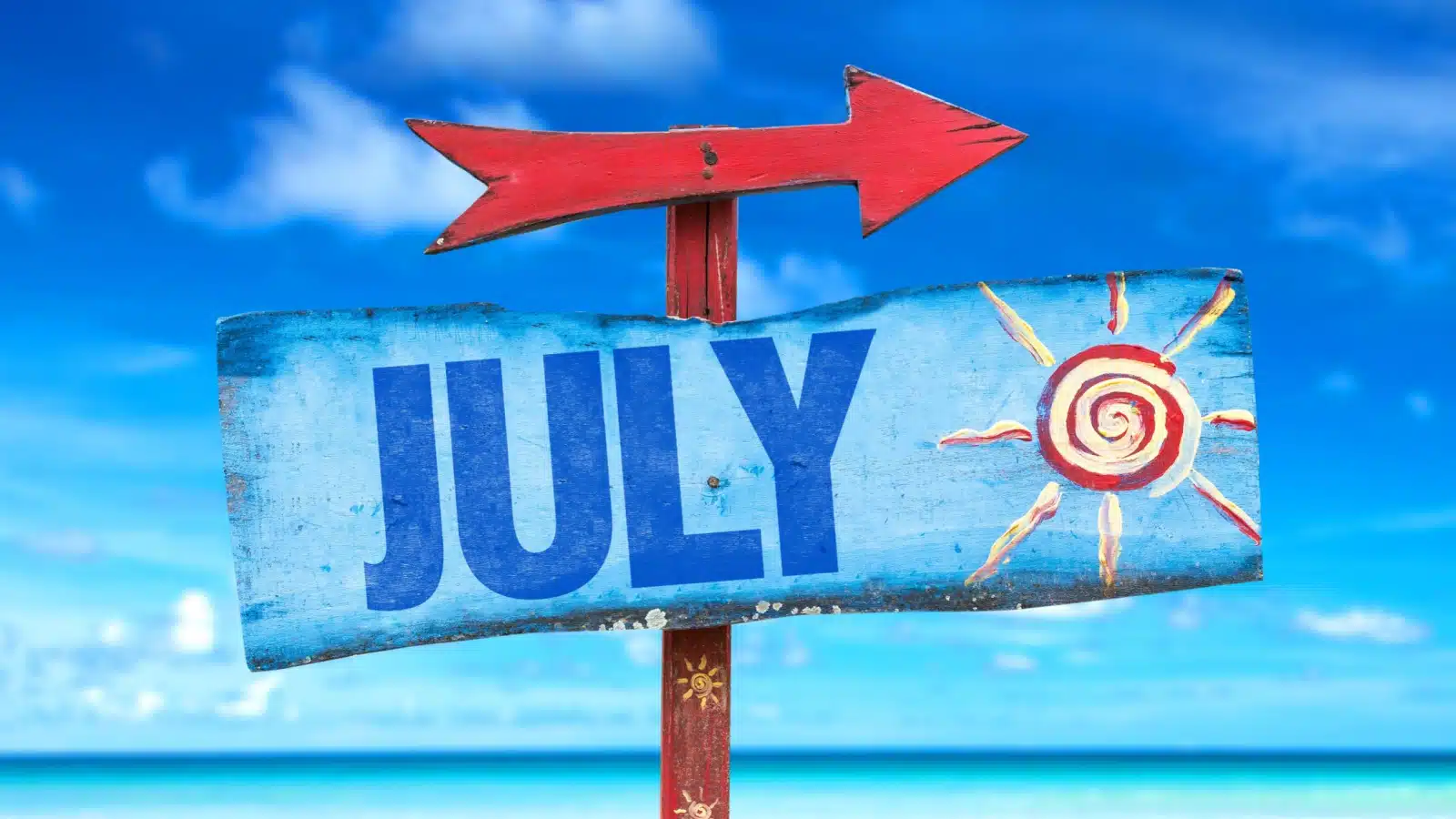 A blue signpost in front of a bright blue sky pointing the way toward July.