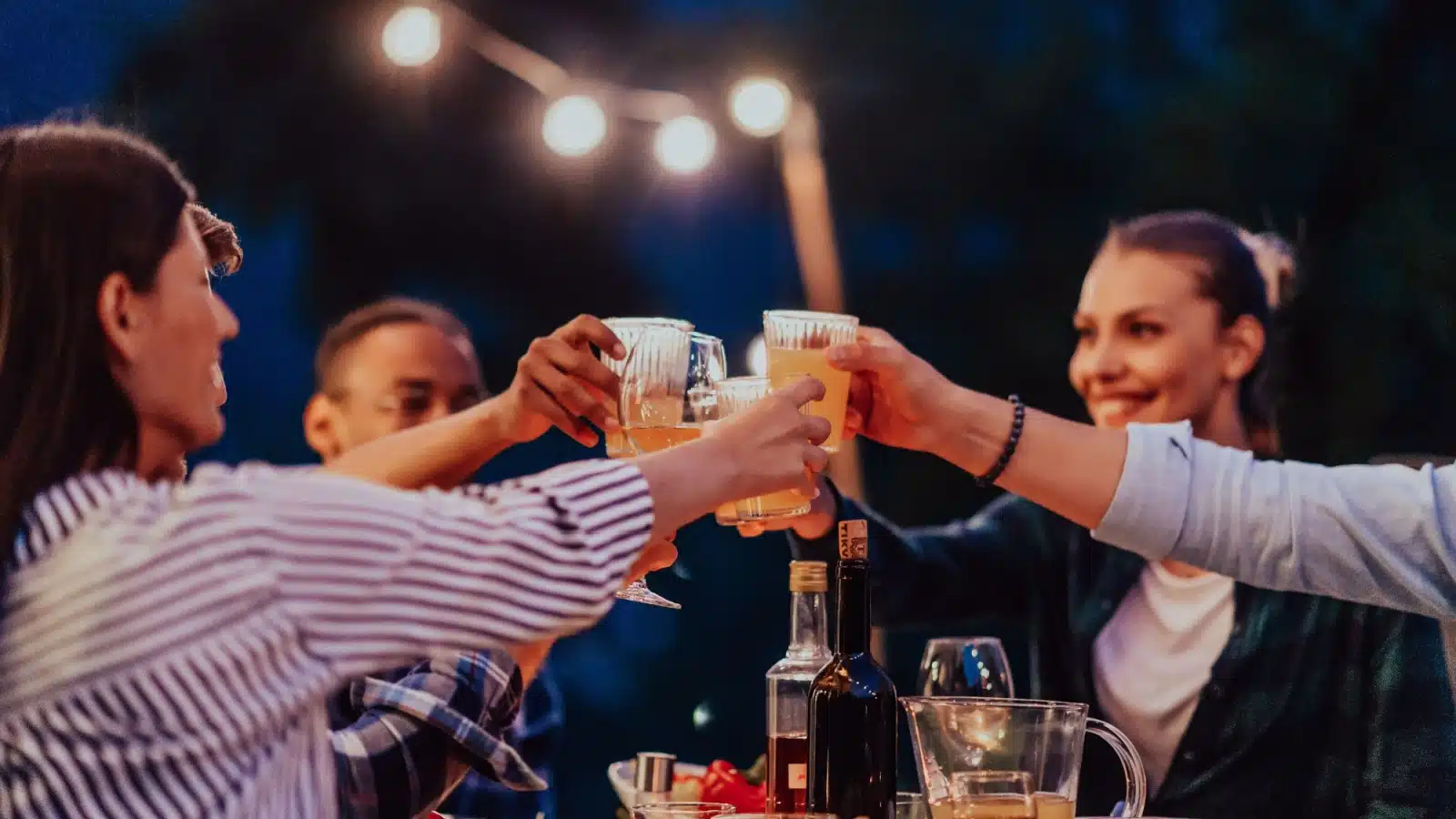 Friends raise their glasses to cheer the outdoor evening meal.