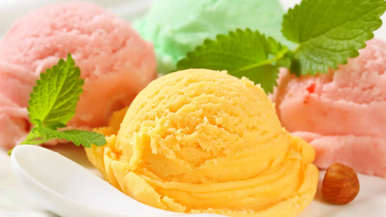 Colorful scoops of fruity sherbet ice cream in a bowl.