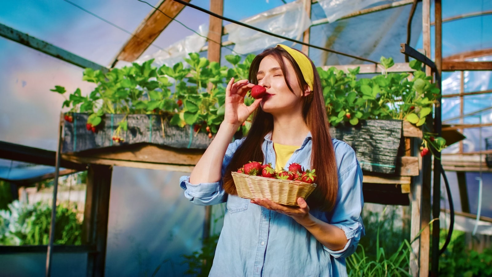 A woman smells a fresh strawberry to represent the best summer scents.