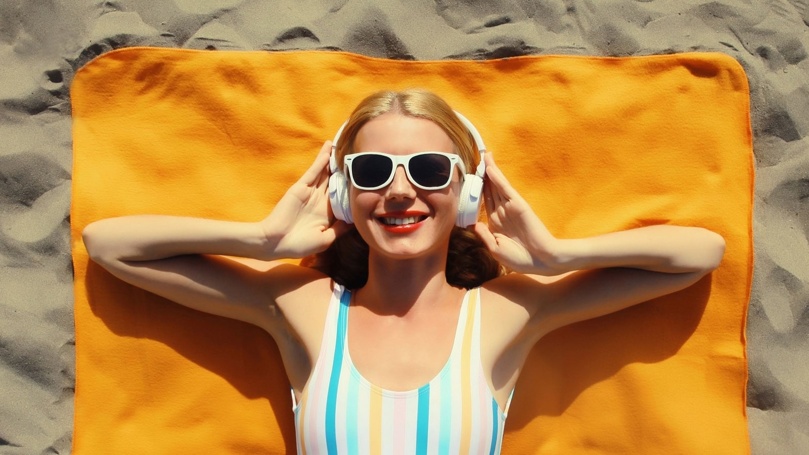 A woman lies on a towel on the beach, enjoying the summer season.